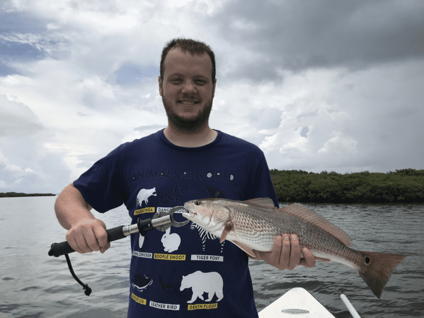 man standing in the ocean with redfish